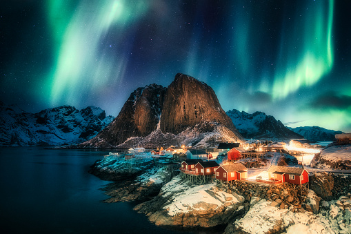Aurora borealis, Northern lights over mountain with fishing village on coastline at Hamnoy, Lofoten islands, Norway