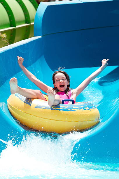 Girl on water slide A young girl on a water slide inflatable ring photos stock pictures, royalty-free photos & images