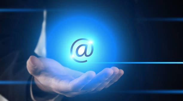 istock Contact us concept, @ at symbol, hand showing at symbol hologram graphical user interface 1373380631