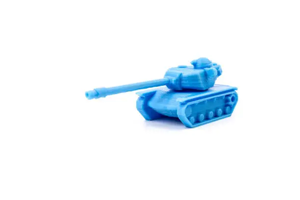 Photo of Toy tank of blue color. Close-up of little plastic ABS model. Blue filament. Objects printed by 3d printer Isolated on white background.