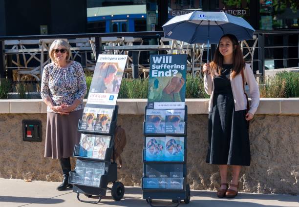 Smiling Jehovah's Witnesses standing next to their Jehovah witness books and pamphlets Sacramento, CA, USA - May 20, 2019:  Smiling Jehovah's Witnesses standing in the street next to their books and pamphlets lookout tower stock pictures, royalty-free photos & images