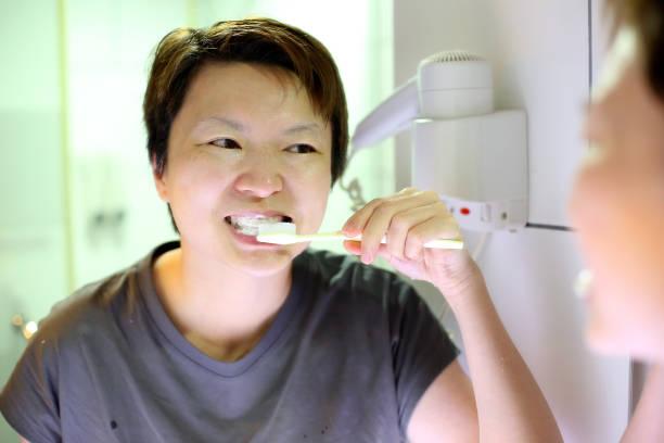 An Asian woman is brushing her teeth in the morning.