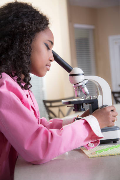 istock Young teen studies science with microscope in her home. 1373435090