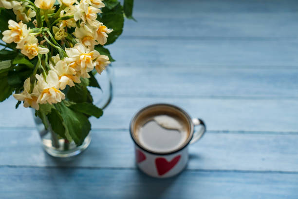 Morning cup of coffee and spring daffodil flowers on blue rustic background.Beautiful breakfast for Women day, Mother day.