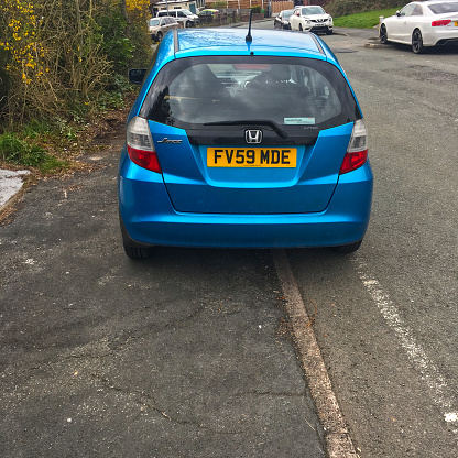 Manchester, England UK- April 13, 2021 : Car parked completely on the pavement and forcing pedestrians and children to walk out into a busy road