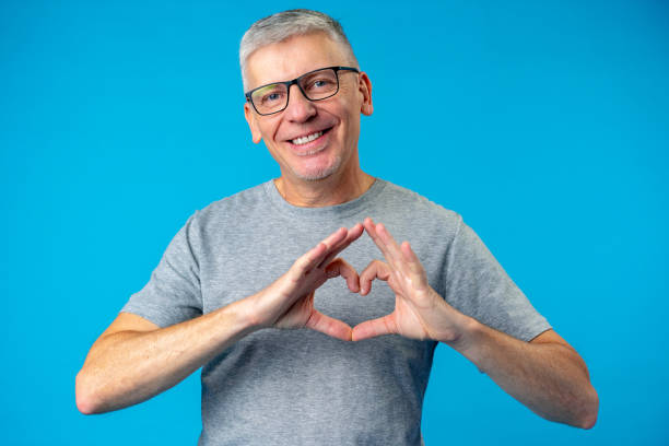istock Middle age handsome man showing heart symbol on blue background 1373464987
