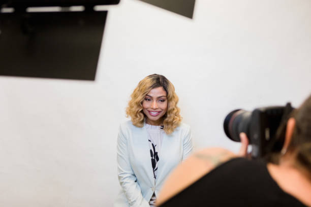 Female television host smiles as photographer takes headshots The mid adult female television host smiles as the unrecognizable female photographer takes publicity photos for the studio. photographers stock pictures, royalty-free photos & images