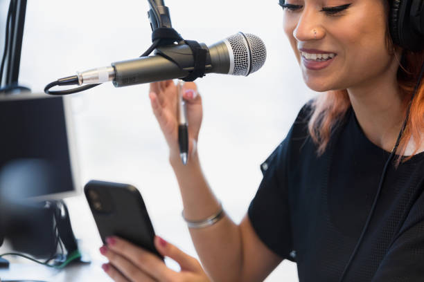 istock Focus on microphone as DJ uses smart phone during show 1373466130