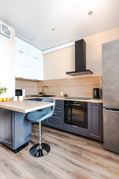 istock Minimalist wooden grey kitchen with handleless facades andbar table, smart storage system. Kitchen room organization 1373469824