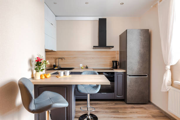 istock Minimalist wooden grey kitchen with handleless facades andbar table, smart storage system. Kitchen room organization 1373470375