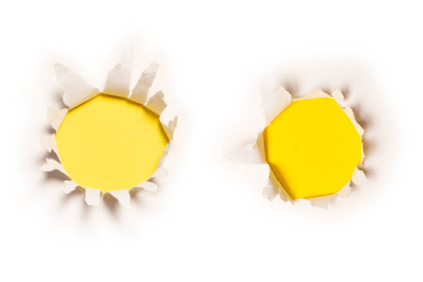 istock A hole in a white paper on a yellow background. 1373474738