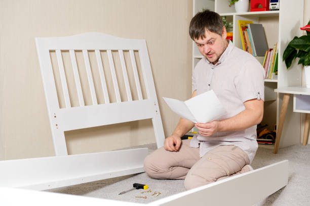 istock A man with instructions for assembling furniture is going to assemble a children's white wooden crib in a children's bedroom. 1373482137