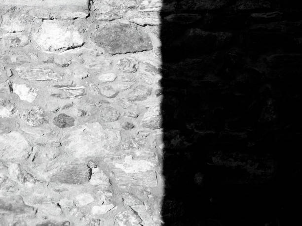 stone wall half in light and half in shadow in black and white
