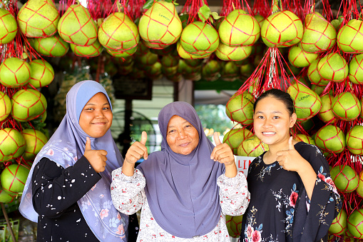 A Muslim store owners selling fresh pomelo fruits cheerfully.