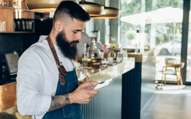 istock Handsome Barista Using Digital Tablet in a Cafe 1373505699
