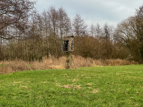 A hunting high seat in a field next to a river in winter.