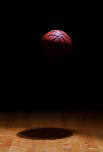 spot da basket illuminato sospeso in aria su uno sfondo nero sopra un pavimento di acero in legno duro - hanging basket foto e immagini stock