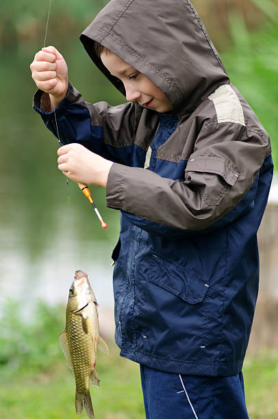 istock Cute boy fishing and holding carp 137355052