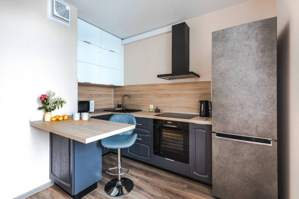 istock Minimalist wooden grey kitchen with handleless facades andbar table, smart storage system. Kitchen room organization 1373559759