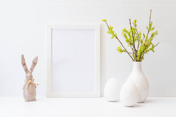 istock Home interior with easter decor. Mockup with a white frame and willow branches in a vase, easter eggs on a light background 1373559864