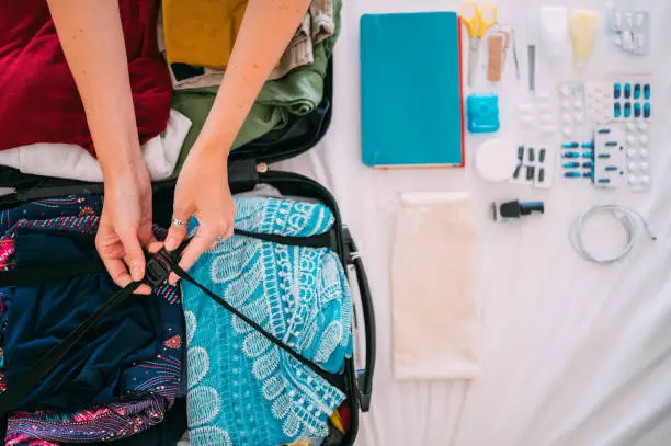 Photo of Directly above of woman's hand preparing summer luggage
