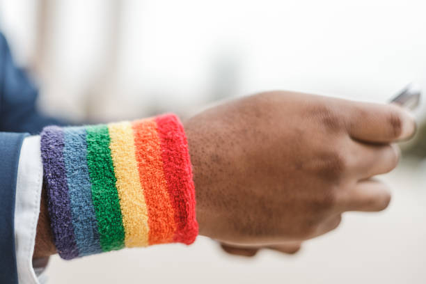 성소수자 팔찌와 아프리카 계 미국인 남자의 매우 클로즈업 보기. 다양성 개념 - gay pride wristband rainbow lgbt 뉴스 사진 이미지