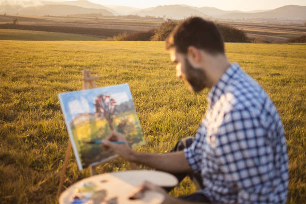 istock Man painting in nature on canvas at sunset 1373575346