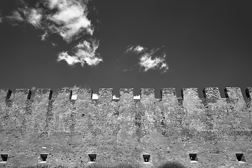 battlements of a medieval wall, the Venetian castle of Frangokastello against the sky on the island of Crete in Greece, monochrome