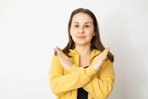 Portrait of young Caucasian woman girl with dark hair with her arms crossed in front of her chest. Concept of Break The Bias campaign