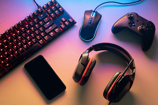 Concepto de espacio de trabajo gamer. configuración de juegos. vista superior de un equipo de juego, teclado, mouse, gamepad, joystick, auriculares y un teléfono inteligente en un escritorio colorido photo