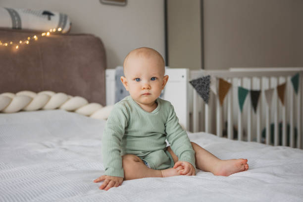 istock Adorable barefoot child smiling while sitting on bed 1373624432
