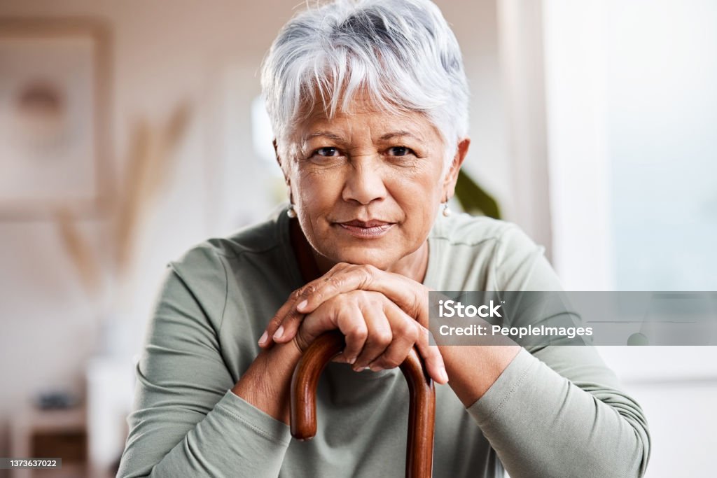 Shot of a senior woman leaning in her walking stick at home Weighed down and blue Senior Adult Stock Photo