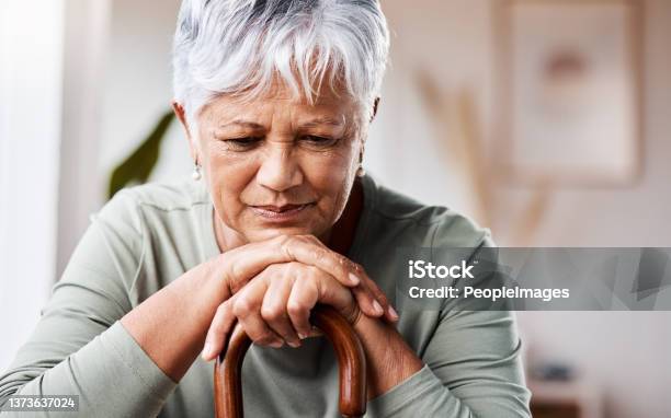 Shot Of A Senior Woman Leaning In Her Walking Stick At Home Stock Photo - Download Image Now