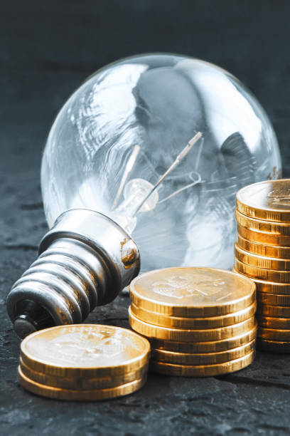 istock Energy saving.Old lamp. Money coins on a dark background. Energy saving. Stack of coins 1373638631