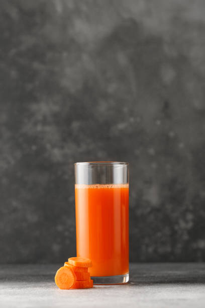 Freshly squeezed juices in glass on dark table. Carrot juice for menu. Mock up