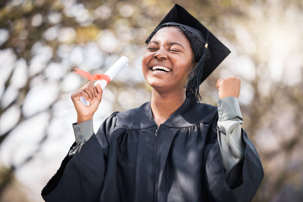 졸업일에 응원하는 젊은 여성의 초상화 - graduation women fist celebration 뉴스 사진 이미지