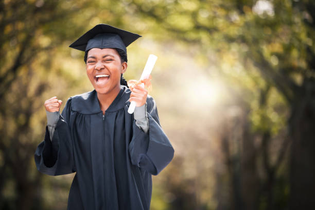 졸업일에 응원하는 젊은 여성의 초상화 - graduation women fist celebration 뉴스 사진 이미지