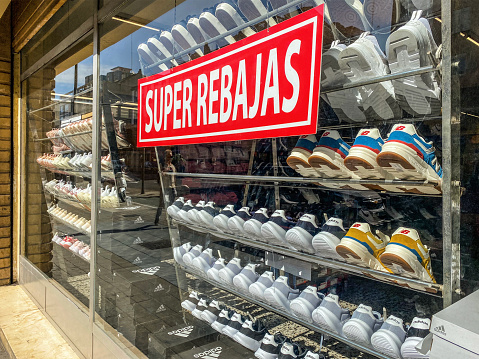 Valencia, Spain - February 28, 2022: Store window with lots of sport shoes offering super sale. Many times in the year there are huge discounts in clothing stores that people take advantage of