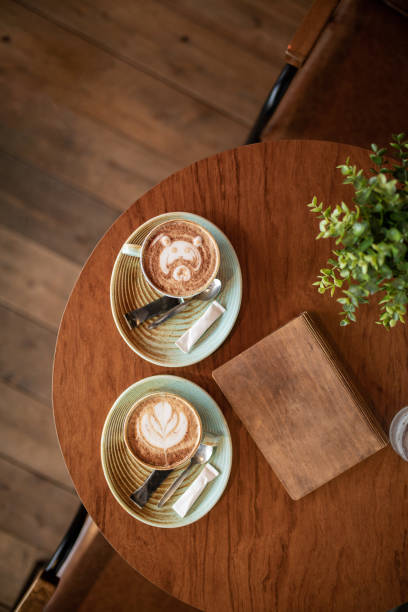 Two cups of fresh coffee with latte art on wooden table in coffee shop stock photo