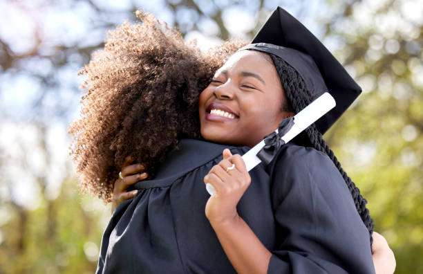 Shot of a young woman hugging her friend on graduation day stock photo