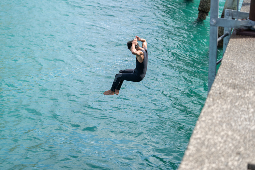 Local boys jump following one and other off Tolaga Bay Wharf enjoying risky behaviour