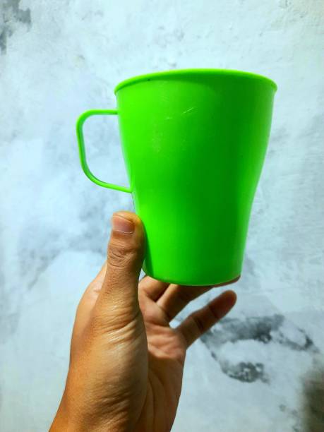 istock a person's hand holding a green plastic cup 1373689051
