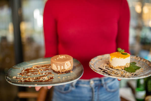Unrecognizable waitress carrying two delicious cakes on plate in cafe