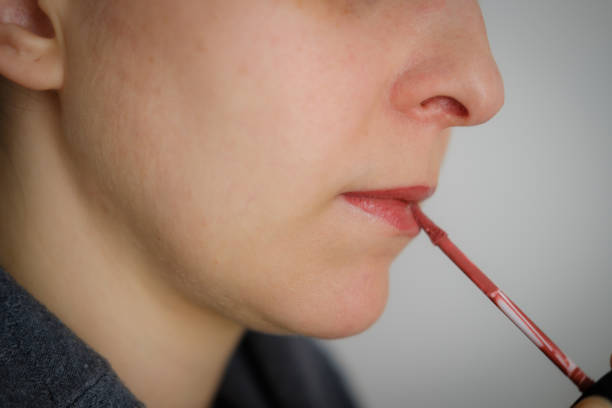 istock woman putting on red lipstick 1373728053