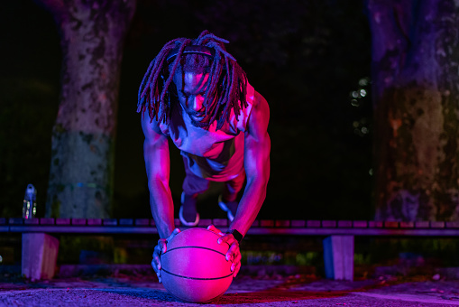 A Black-ethnic basketball player is doing push-ups.