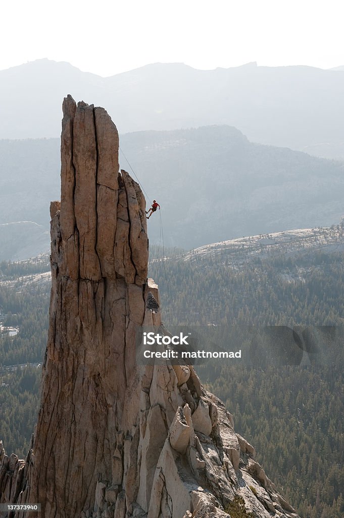 Descending off pinnacle. A climber rappels off of Eichorn pinnacle in Yosemite National Park, CA. Vertical orientation. Achievement Stock Photo