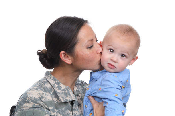 Military Asian Woman Kisses Child Asian woman and baby on white background taken in Long Beach, California in February of 2022. proud army mom stock pictures, royalty-free photos & images