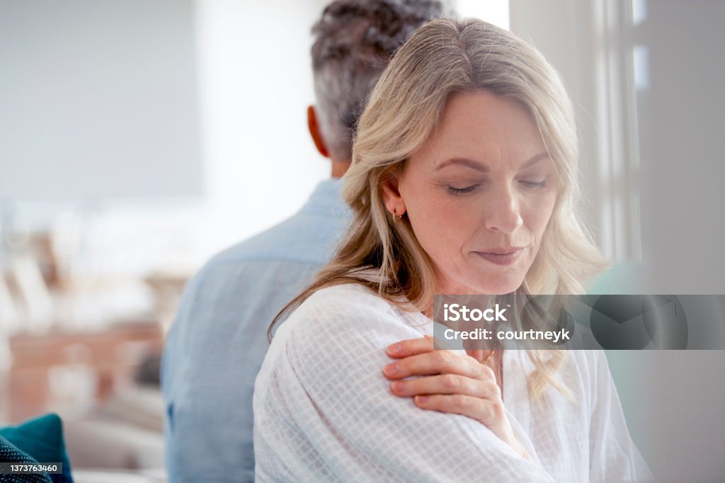 Mature couple fighting at home sitting on the sofa. Mature couple fighting at home sitting on the sofa. They are sitting back to back not talking. The woman looks sad and depressed Couple - Relationship Stock Photo
