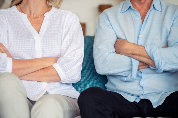 Mature couple fighting at home sitting on the sofa. stock photo