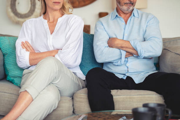 Mature couple fighting at home sitting on the sofa